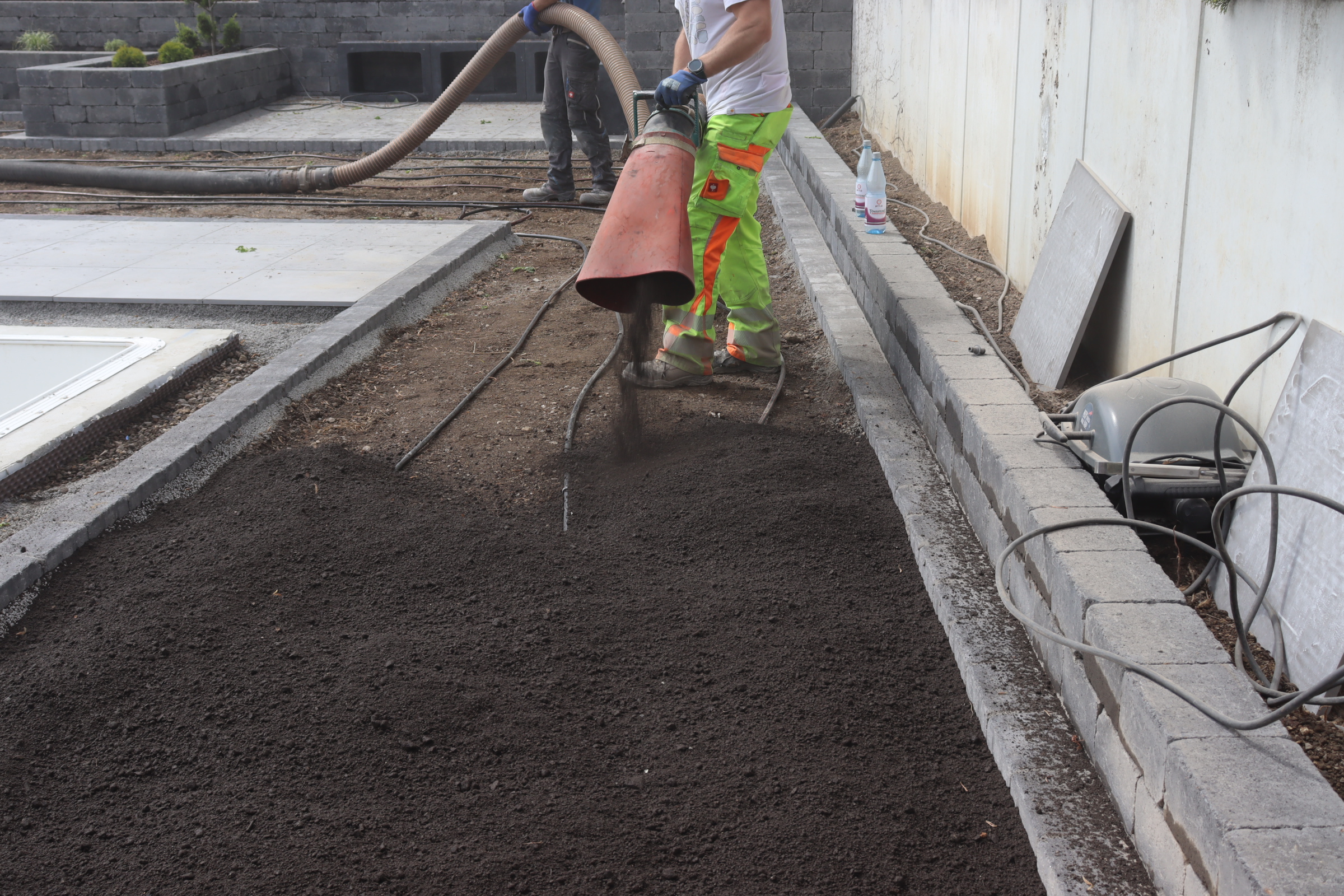Zwei Personen stehen auf einem dach und halten einen Turboliftschlauch, aus welchem Substrat ausgeblasen wird