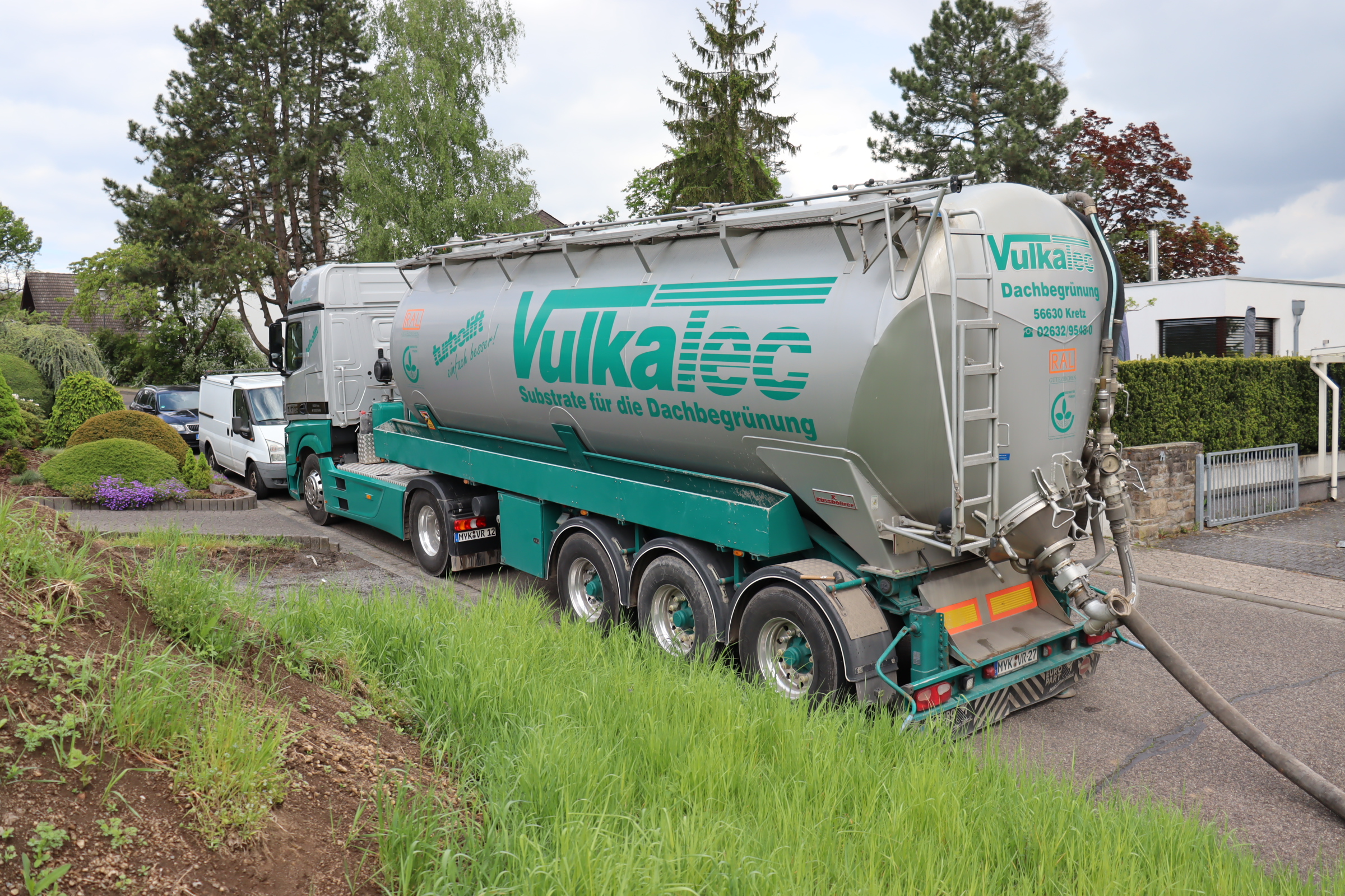 Vulkatec Silofahrzeug steht mit angeschlossenem Schlauch vor einer begrünten Fläche